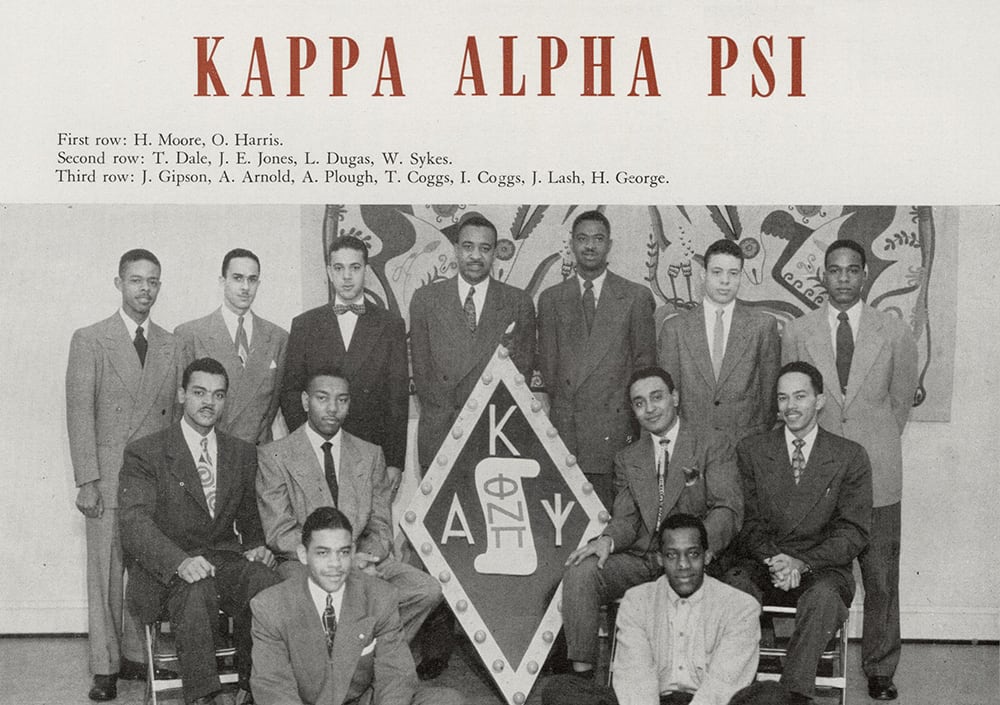 Thirteen Kappa Alpha Psi fraternity men pictured around their fraternity seal. 