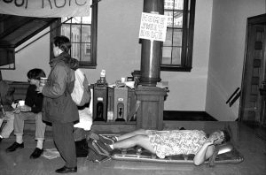 A student lays on a sleeping cot, with a handmade “Home Sweet Home” behind him during a sit-in outside Chancellor Donna Shalala's office to protest the ROTC policy on gays and lesbians.