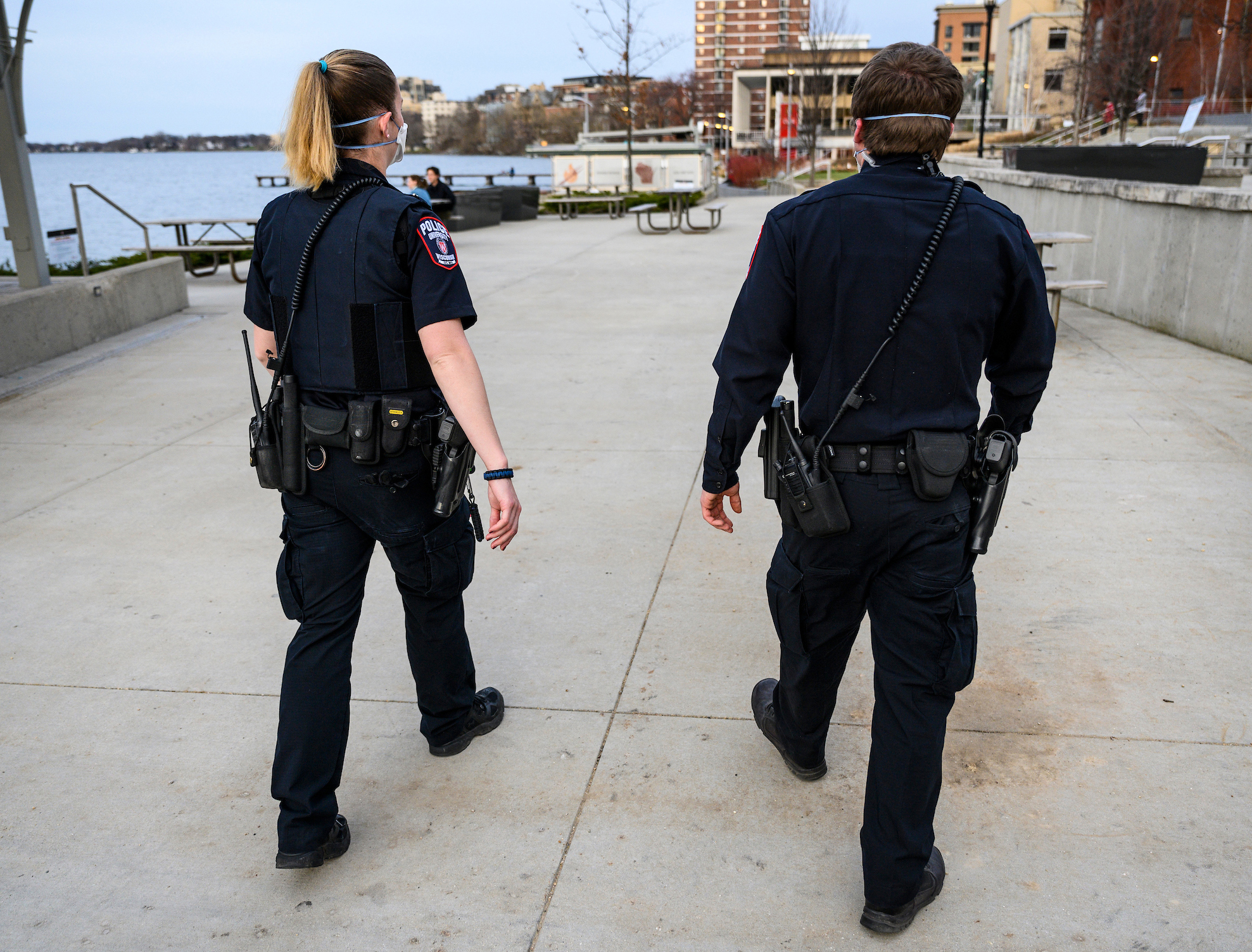 Two UWPD officers in dark blue uniforms are seen from behind walking on the Memorial Union Terrace.